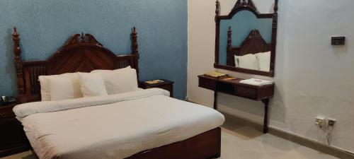 1 dormitorio con 1 cama grande y espejo en Hotel Shelton Palace en Multán