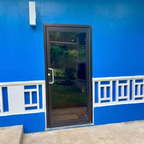 a blue house with a door with a window at Ngermid Oasis - Vibrant 2 BD/1 BA Duplex in Ngermid