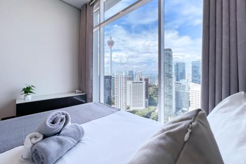a bedroom with a large window with towels on a bed at Soho Suites KLCC by Leala in Kuala Lumpur