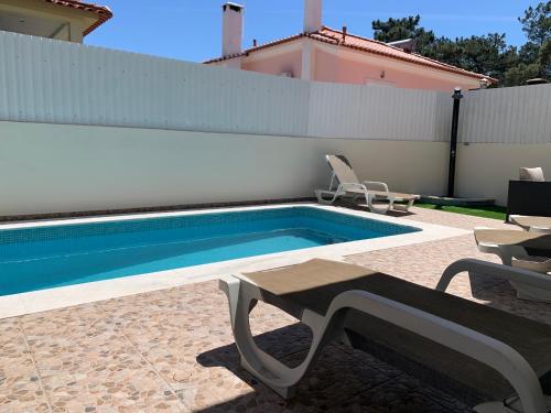 a swimming pool with a table and chairs next to a house at Villa Luxsomar in Charneca