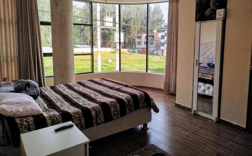 een slaapkamer met een bed en een groot raam bij Hermosa casa in Huancayo