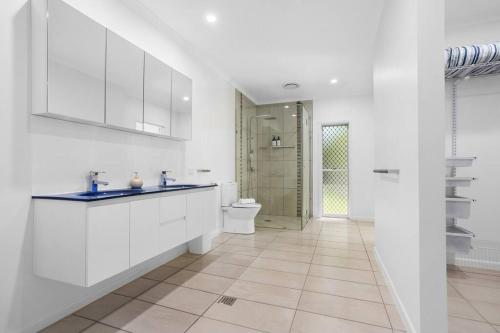 a white bathroom with a toilet and a sink at Trinity Beach Stunner - Tropical Entertainer in Trinity Beach
