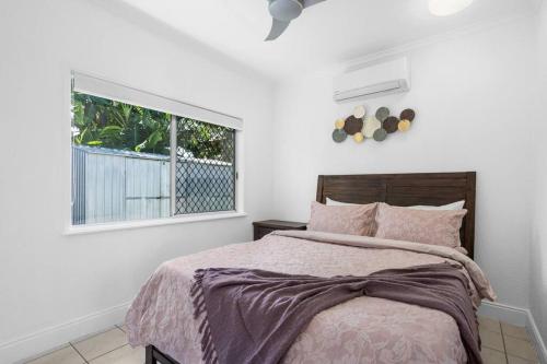 een slaapkamer met een bed en een raam bij Trinity Beach Stunner - Tropical Entertainer in Trinity Beach