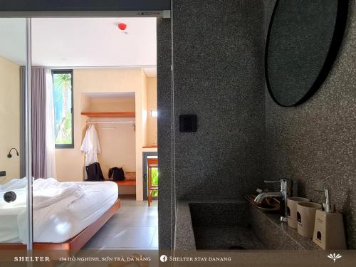 a bedroom with a bed and a bathroom with a mirror at Shelter Stay Da Nang in Da Nang