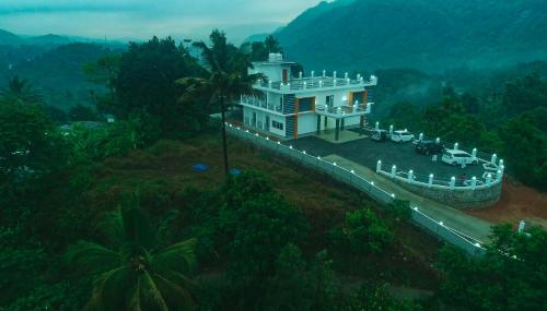 a large white house on a hill in the jungle at Karickanattu Nature Resort in Idukki