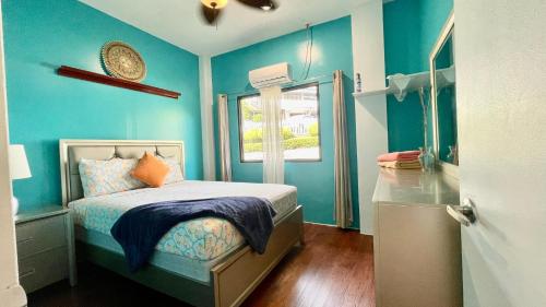a blue bedroom with a bed and a window at Ngermid Oasis - Vibrant 2 BD/1 BA Duplex in Ngermid