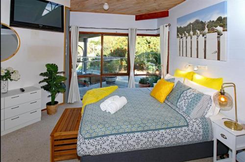 a bedroom with a bed with yellow pillows and a television at Coota Views in Mallacoota