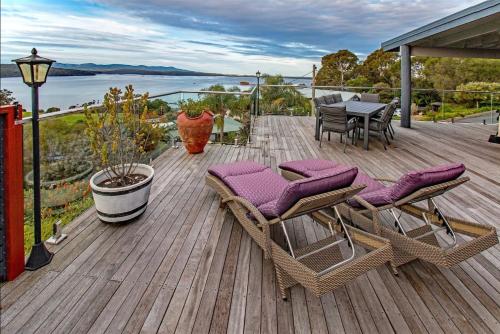 a wooden deck with chairs and a table on a house at Coota Views in Mallacoota