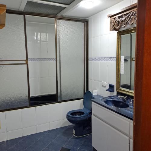 uma casa de banho com um WC azul e um lavatório. em Fortaleza Diosa Chia em Chía
