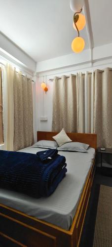 a bedroom with a bed with blue sheets and curtains at Mirik Homestay in Mirik