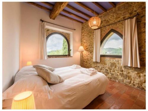 a bedroom with a large bed with two windows at Villa Fienile Design in SantʼAppiano