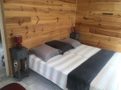uma cama num quarto com uma parede de madeira em Natura em Masseboeuf