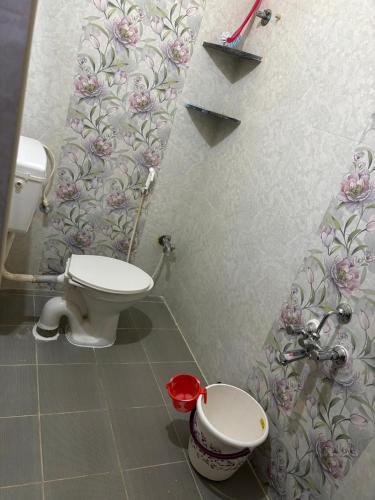 a bathroom with a toilet and a flowery wallpaper at VARAHA GUEST INN LUXURY ROOMs in Tirupati