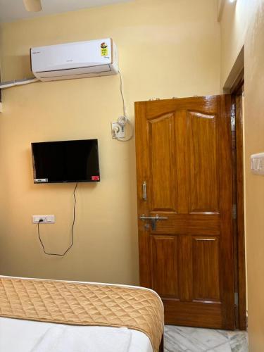 a bedroom with a bed and a tv and a door at VARAHA GUEST INN LUXURY ROOMs in Tirupati