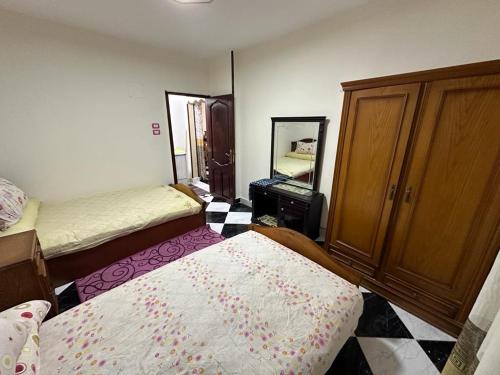 a bedroom with two beds and a dresser and a mirror at شقه عائليه قريبه من جميع الخدمات in Port Said