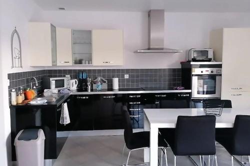 una cocina con electrodomésticos en blanco y negro y una mesa en Le cocon rochois en Roches-sur-Marne