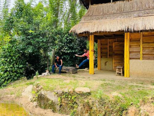un grupo de personas sentadas fuera de una cabaña en Arana Rathnaella Eco Lodge, en Hassalaka