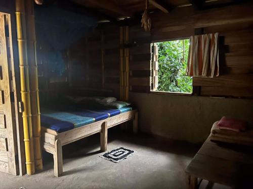 Cama pequeña en habitación con ventana en Arana Rathnaella Eco Lodge, en Hassalaka