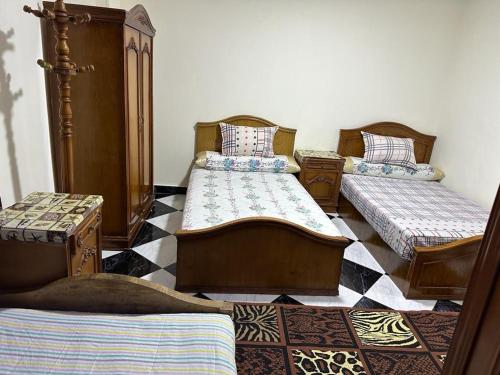 three beds in a room with a checkered floor at شقه عائليه قريبه من جميع الخدمات in Port Said