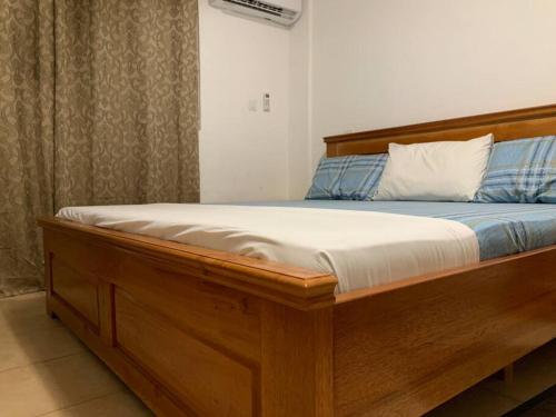 ein Bett mit einem Holzrahmen in einem Zimmer in der Unterkunft Modern Cozy 2Bedroom Space near KNUST & Kumasi Airport in Kumasi