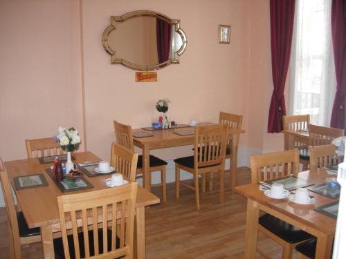 a dining room with wooden tables and chairs and a mirror at Longfield Guest House in Dover