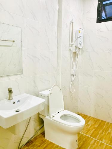 a white bathroom with a toilet and a sink at Suanvadee Resort สวนวดี รีสอร์ท in Don Sak