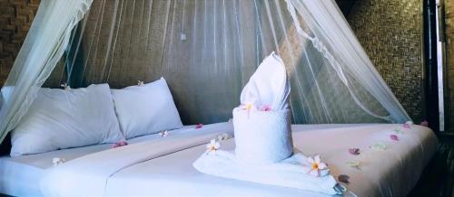 a bed with a white canopy and a bed with flowers on it at Mahkota Atia Bungallow in Praya