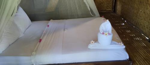 a white bed with a cup on top of it at Mahkota Atia Bungallow in Praya