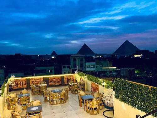 eine Dachterrasse mit Tischen und Stühlen in der Nacht in der Unterkunft king of pharaohs pyramids view in Kairo