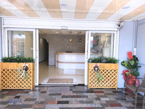 an open door of a store with two potted plants at Green Island Sweet Hotel in Green Island