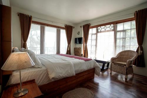 a bedroom with a bed with a lamp and windows at MISSION VALLEY Kalimpong in Kalimpong