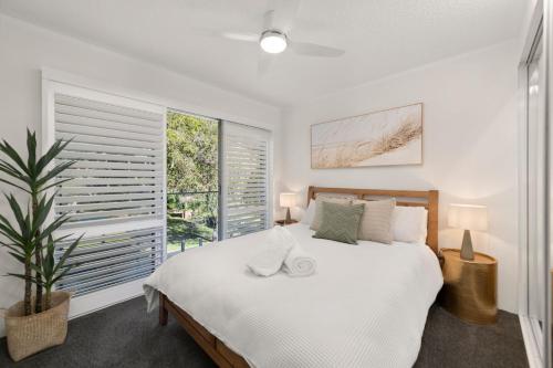 a bedroom with a white bed and a large window at Perfect Coastal Getaway-Metres to Shoal Bay Beach in Nelson Bay