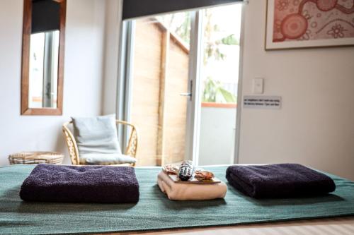 a bed with two purple pillows and a clock on it at Nomads St Kilda in Melbourne