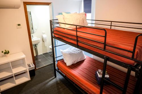 a couple of bunk beds in a room with a mirror at Nomads St Kilda in Melbourne
