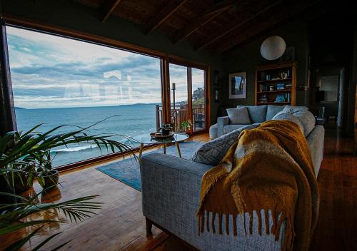 a living room with a couch and a view of the ocean at Waterfront - Bluff Beach House, Park Beach in Dodges Ferry