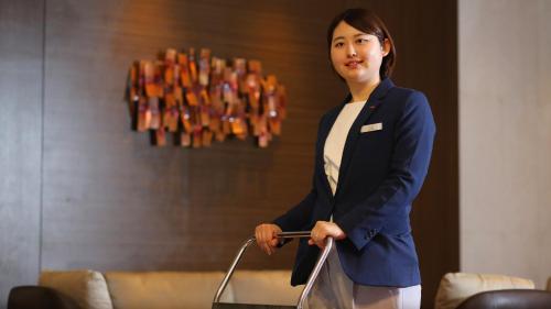a woman in a blue suit holding a cart at ANA Crowne Plaza Niigata by IHG in Niigata