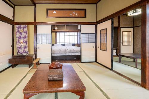 甲府市にある宝乃小宿 TAKARA no Koyadoのテーブルのある部屋とベッドのある部屋