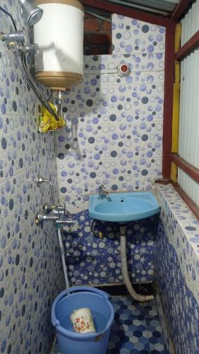 ein Badezimmer mit Waschbecken und einem blauen Eimer in der Unterkunft Benus in Darjeeling