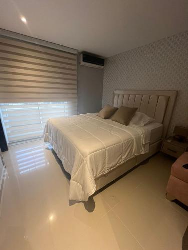 - une chambre avec un grand lit blanc et une fenêtre dans l'établissement Hermoso Apartaestudio Norte de Barranquilla, à Barranquilla