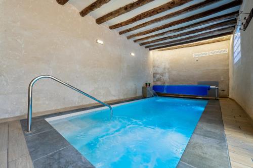 a large indoor pool with blue water in a room at Arassa casa rural in Rocafort de Queralt