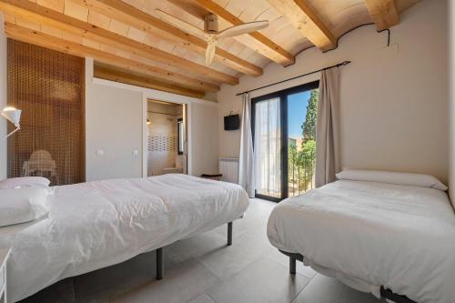 a bedroom with two beds and a large window at Arassa casa rural in Rocafort de Queralt
