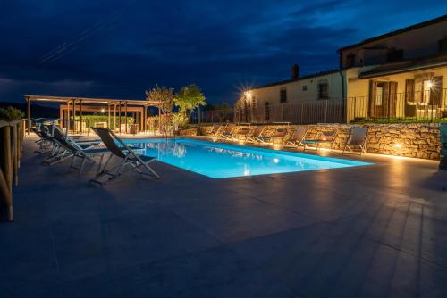 a swimming pool with lounge chairs and a building at Villanovia Country House in Volterra