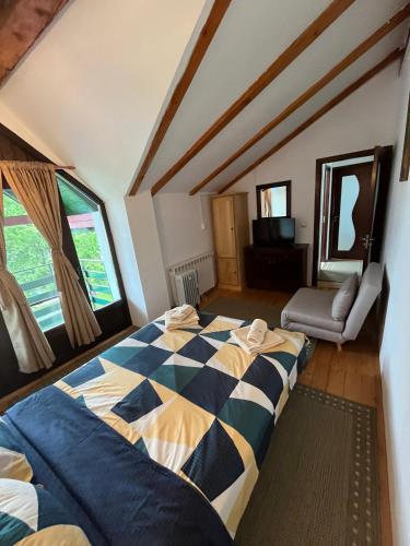 a bedroom with a large bed and a chair at Casuta Anei in Eşelniţa