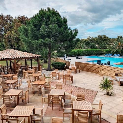 un patio avec tables et chaises et une piscine dans l'établissement Superbe T2 neuf 42m² Cala Rossa (proche mer), à Lecci