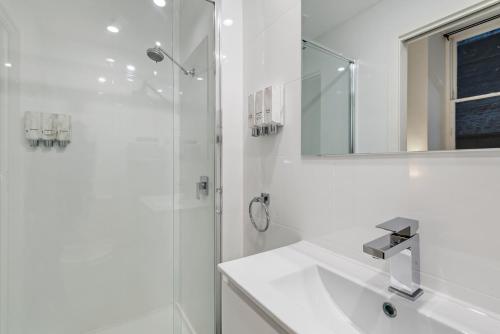 a white bathroom with a sink and a shower at Studio Gem in the Heart of Melbourne in Melbourne