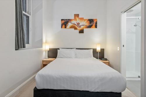 um quarto com uma grande cama branca e 2 candeeiros em Studio Gem in the Heart of Melbourne em Melbourne