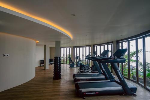 a gym with treadmills and ellipticals in a room with windows at Elevate Bali in Munduk
