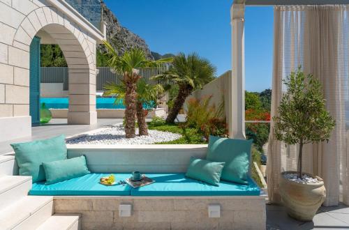 a blue bench on a patio with palm trees at Casa GENI-heated pool, 3 bedrooms, sea views in Omiš