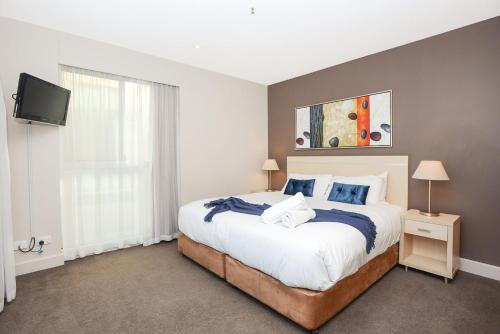 Schlafzimmer mit einem Bett und einem Flachbild-TV in der Unterkunft Pier Apartment - Glenelg Views - No 506 in Adelaide