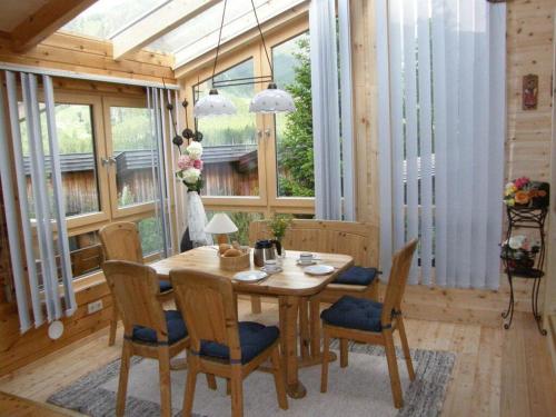 een houten tafel en stoelen in een kamer met ramen bij Schanzer-Hütte Comfortable holiday residence in Hohentauern